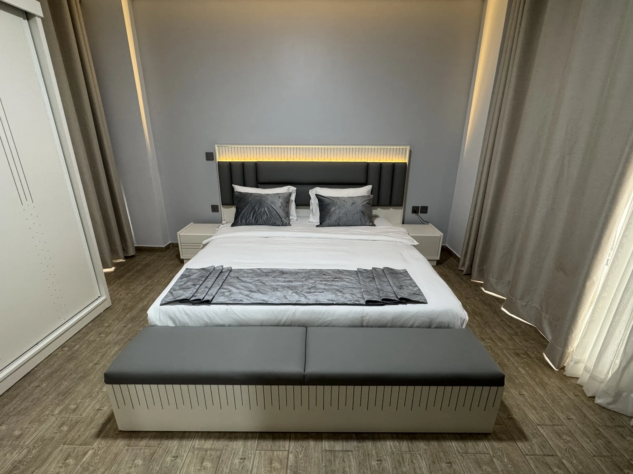 Bedroom with a lit headboard and grey bench