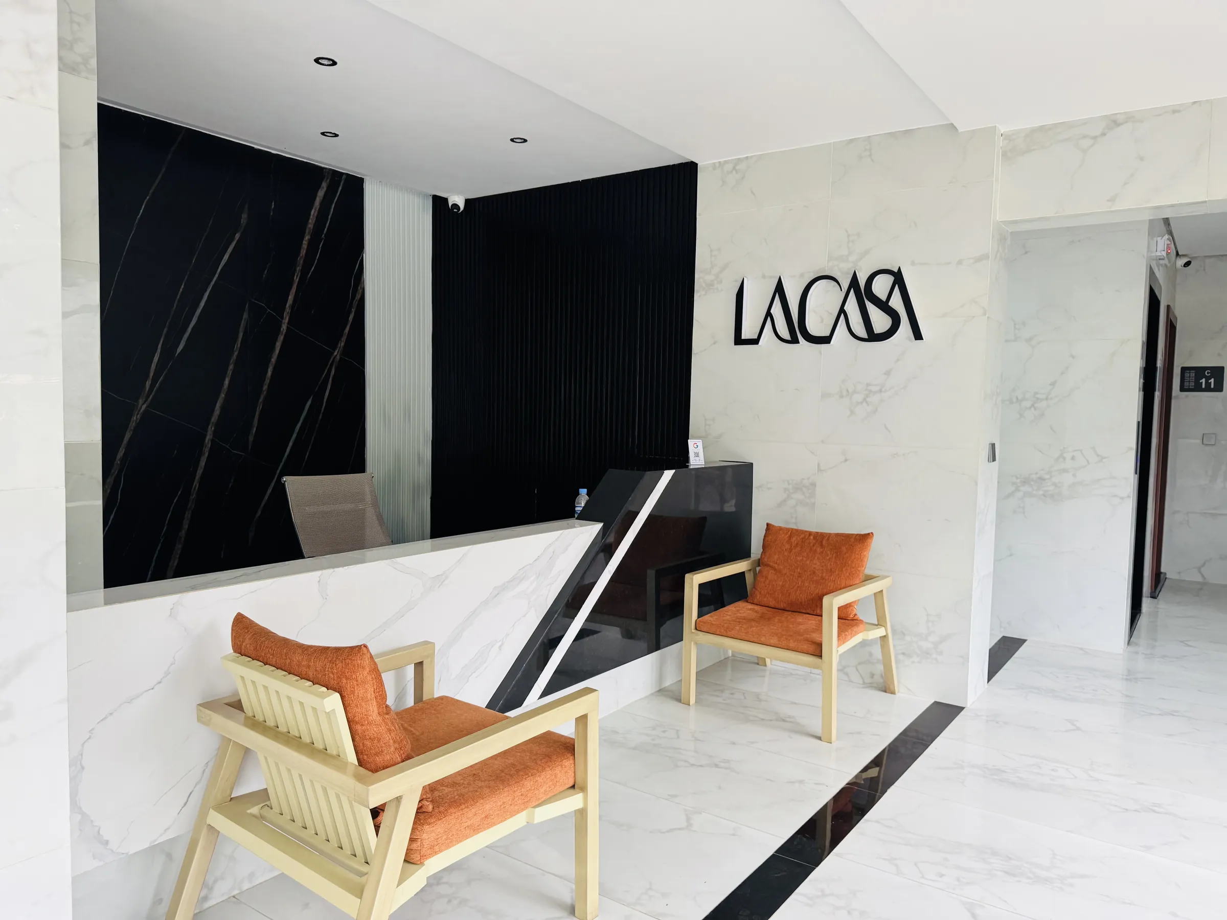 Marble reception with the LA CASA logo and orange armchairs