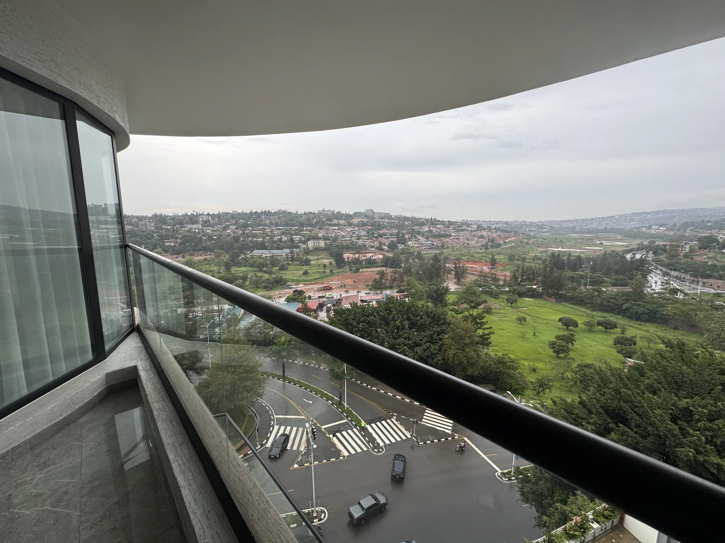 Curved glass balcony overlooking green hills and the city